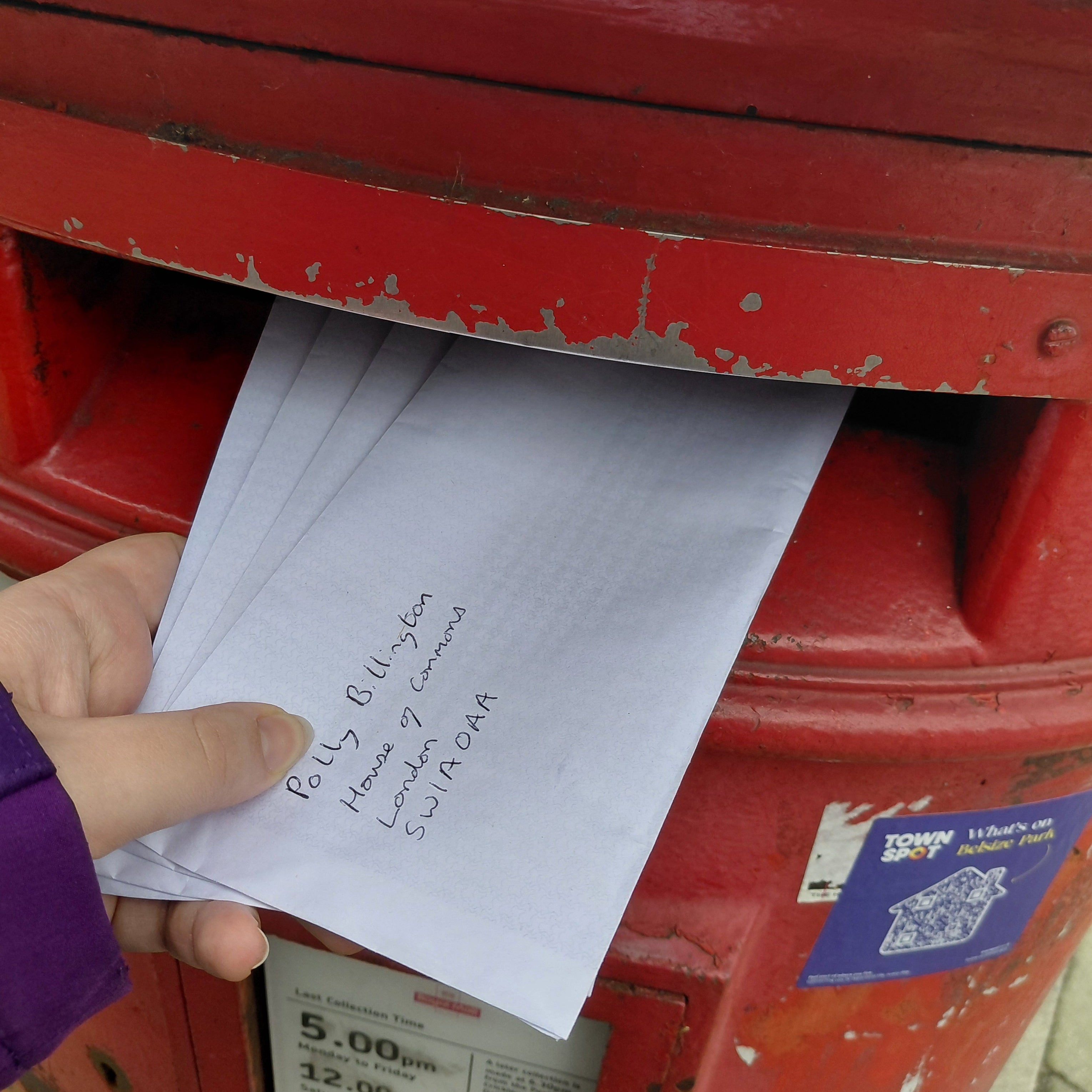Hand placing letters into a red mailbox