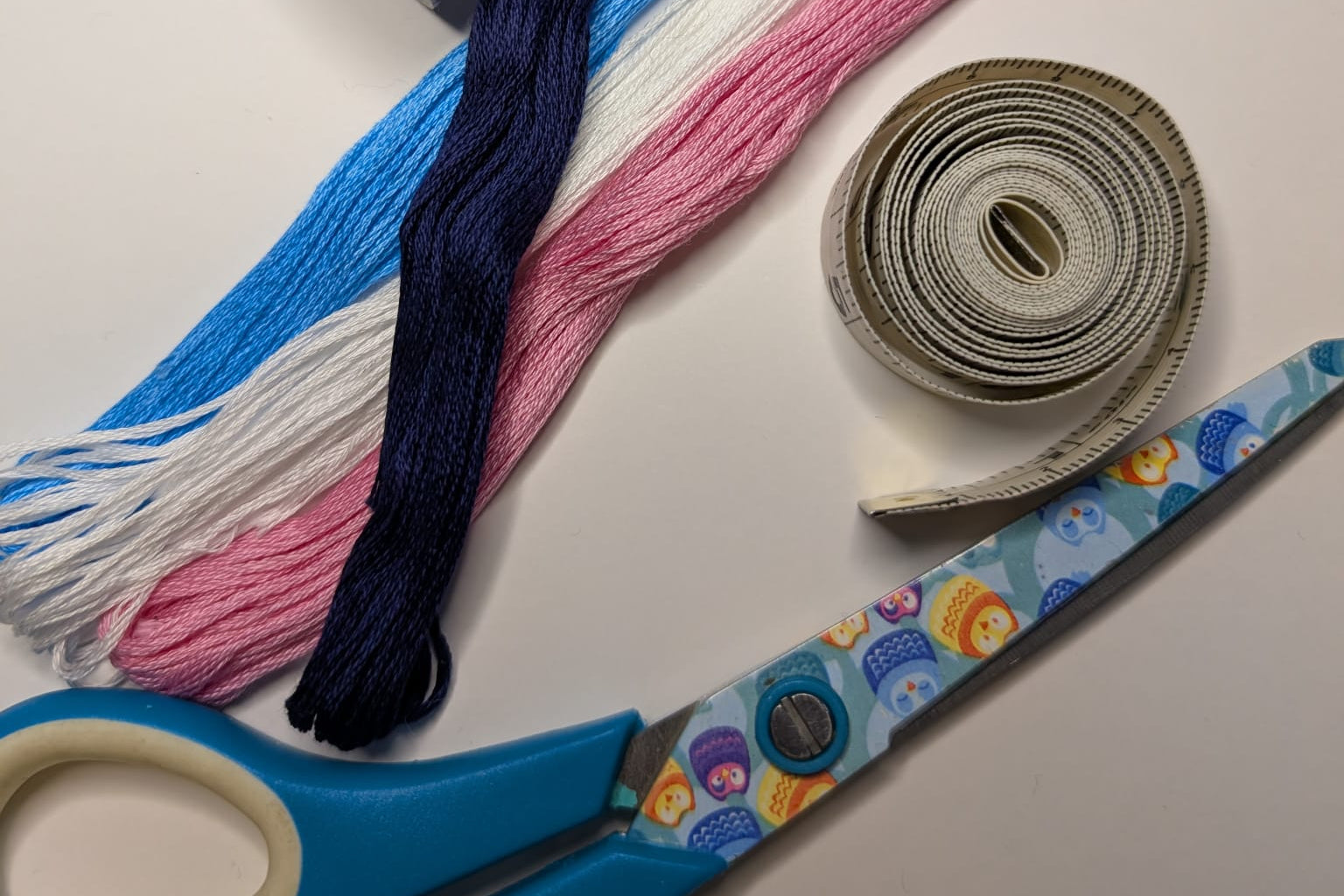 Embroidery threads, scissors, and tape on a light background